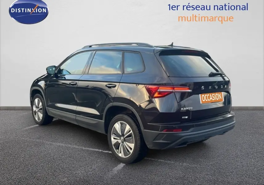 Vue 3/4 arrière droite d'un SKODA KAROQ noir Magic Metal avec jantes bi-ton et feux LED arrière allumés.