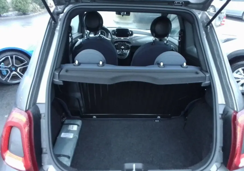 Coffre ouvert en vue arrière d'une FIAT 500 gris foncé, montrant l'intérieur et les sièges avant.