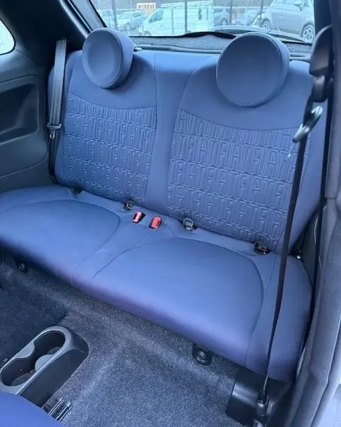 Vue intérieure arrière montrant la banquette arrière gris foncé avec motifs FIAT embossés de la Fiat 500 Hybrid 2022.