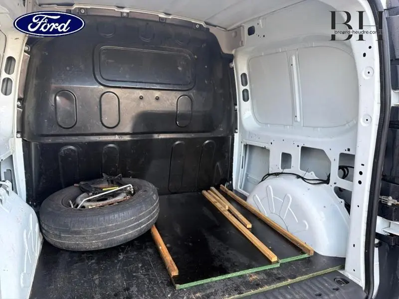 Vue intérieure arrière du fourgon blanc Mercedes Citan 108 CDI Compact montrant l'espace de chargement avec roue de secours.