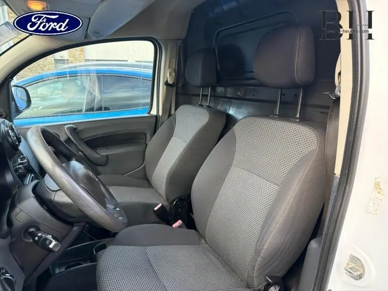 Vue intérieure côté conducteur du Mercedes Citan blanc, montrant les sièges avant gris et la cloison métallique arrière.