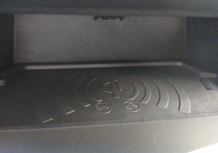 Gros plan sur le chargeur sans fil intégré dans la console centrale de la Peugeot 408 Hybrid blanche.