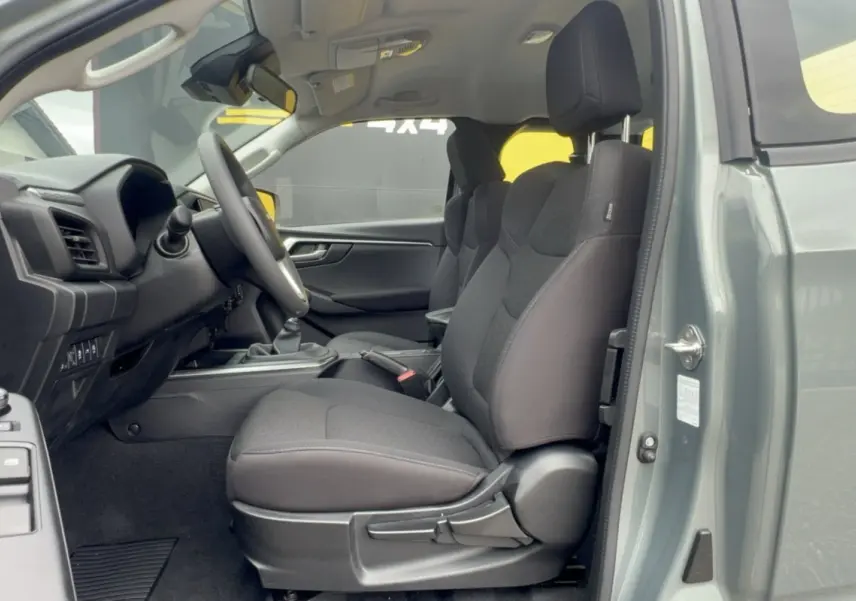 Vue intérieure côté conducteur du pick-up Isuzu D-MAX 2.2 TD vert Inishmore, sièges tissu noirs et tableau de bord visible.
