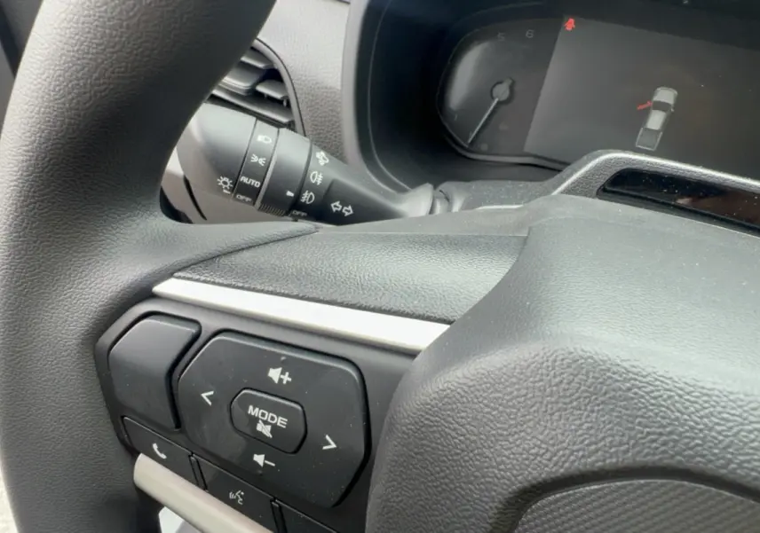 Gros plan sur le volant multifonctions noir de l'Isuzu D-MAX 2026 avec commandes audio et indicateur tableau de bord.