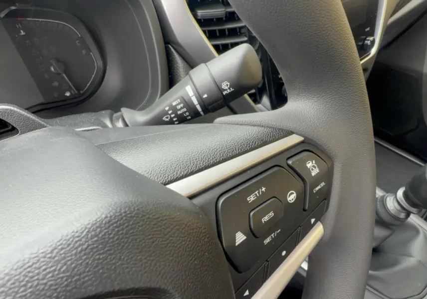 Gros plan sur le volant multifonctions gris foncé de l'Isuzu D-MAX avec commandes de régulateur de vitesse visibles.