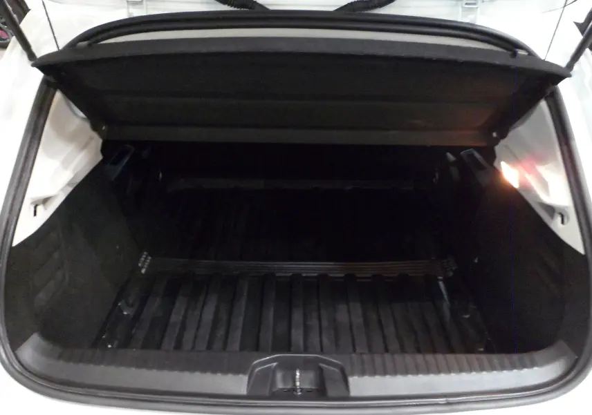 Coffre ouvert de la Renault Clio V Société blanc glacier, montrant un espace de chargement vide et protégé.