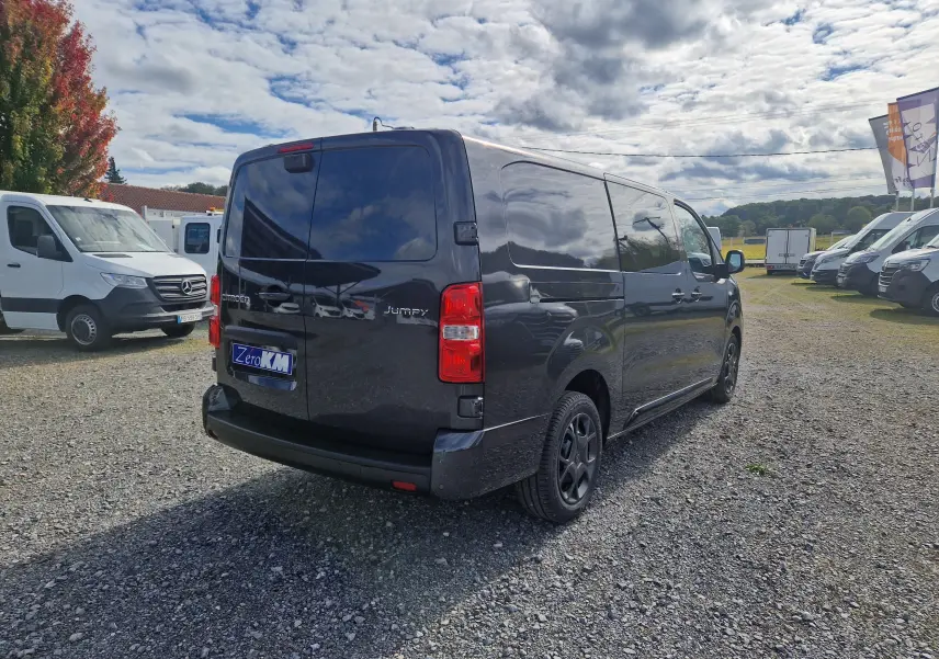 Vue 3/4 arrière droite d’un Citroën Jumpy XL gris titane avec jantes tôles 17 pouces sur un parking extérieur.