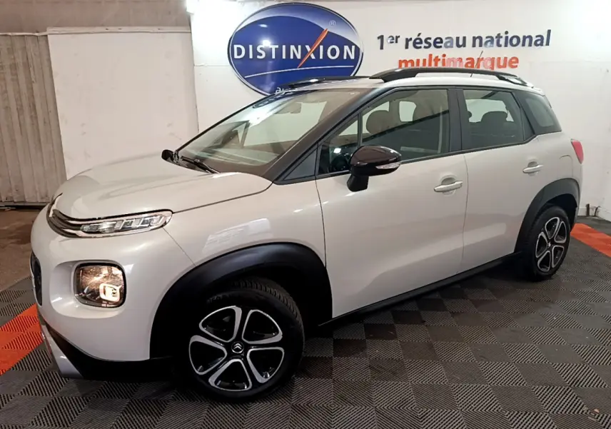 Citroën C3 Aircross blanc vue 3/4 avant droit, avec jantes alliage et barres de toit noires visibles.