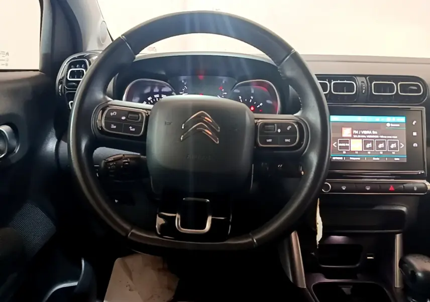 Vue centrée sur le volant cuir noir et le tableau de bord avec écran tactile d'une Citroën C3 Aircross blanche de 2019.