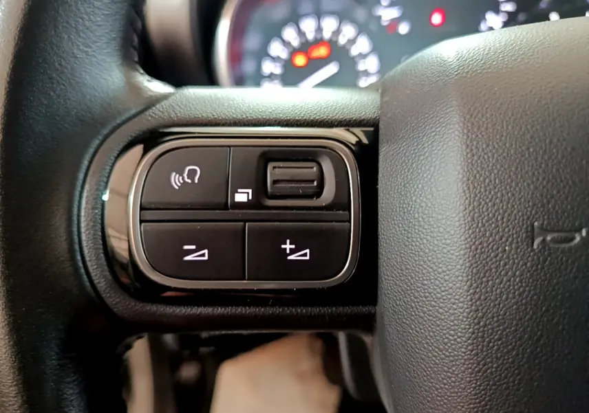 Gros plan sur les commandes multifonctions à gauche du volant cuir du Citroën C3 Aircross blanc de 2019.