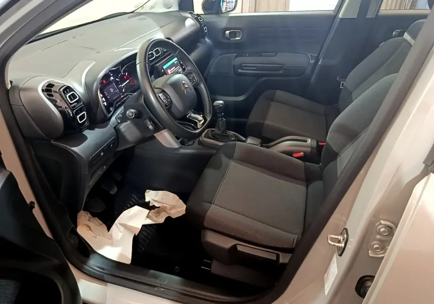 Intérieur avant droit d'une Citroën C3 Aircross blanc, volant cuir, tableau de bord avec écran tactile et sièges gris.