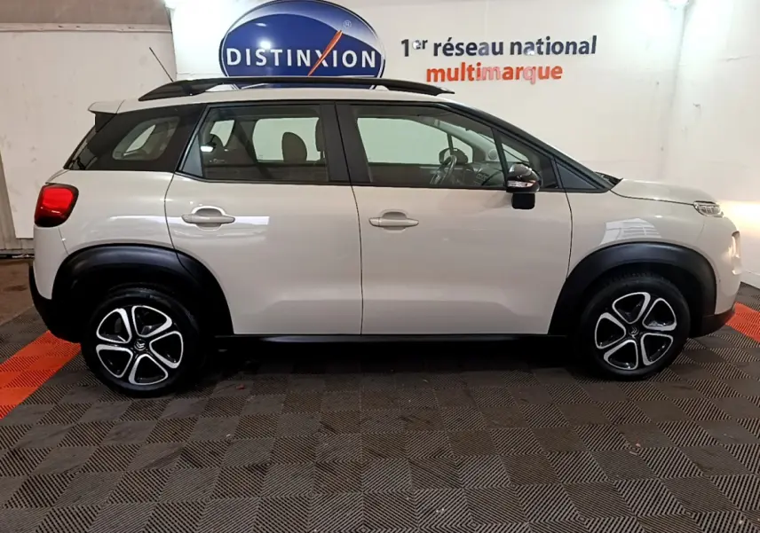 Profil côté gauche d'un Citroën C3 Aircross blanc 2019 avec barres de toit noires et jantes alliage distinctives.