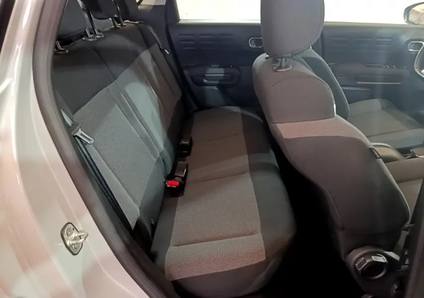 Vue intérieure côté gauche montrant la banquette arrière et les sièges avant noirs du Citroën C3 Aircross blanc.