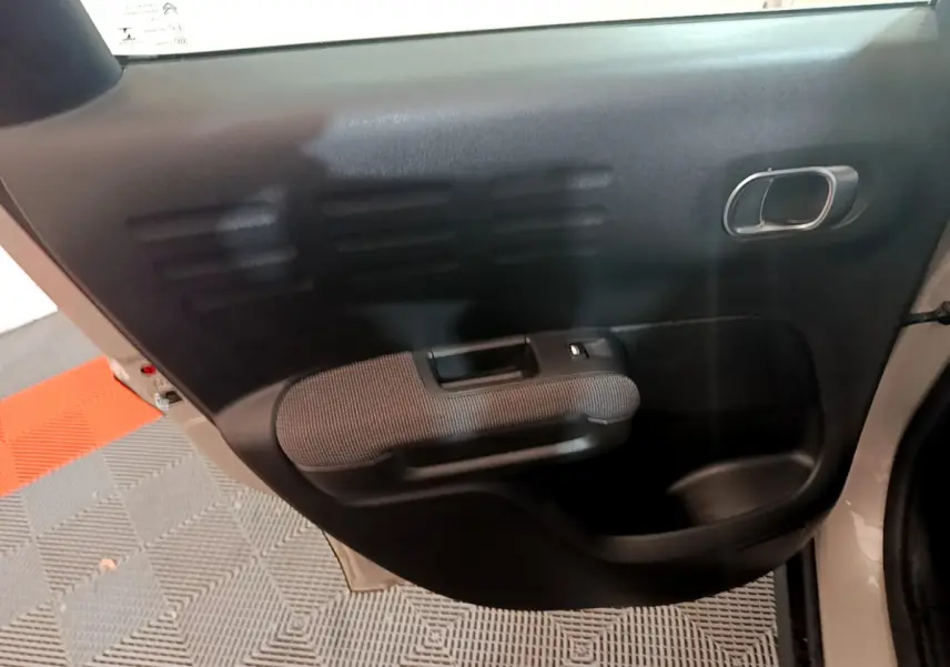 Vue rapprochée de la porte arrière gauche noire intérieure du Citroën C3 Aircross blanc avec poignée et bouton de vitre électrique.