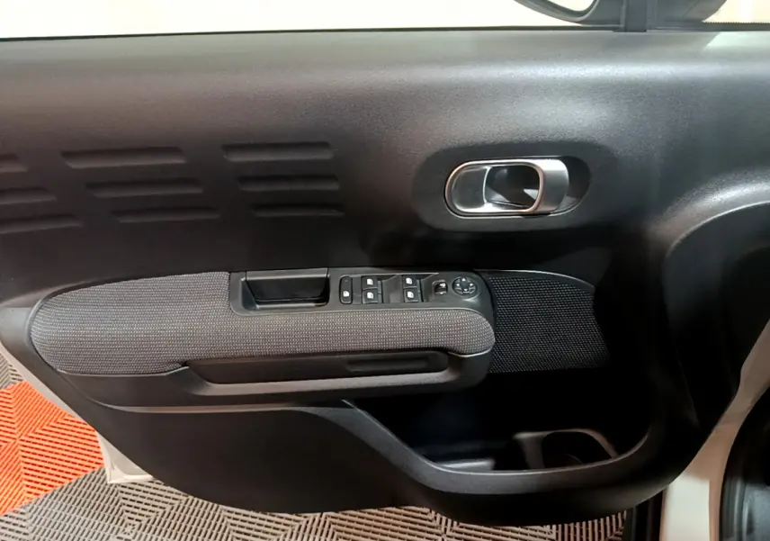 Gros plan sur la porte côté conducteur du Citroën C3 Aircross blanc, montrant la poignée et les commandes des vitres.
