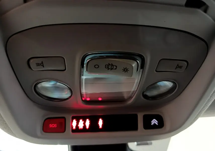 Plafonnier intérieur avec commandes d’éclairage et bouton SOS du Citroën C3 Aircross blanc, vue en contre-plongée.