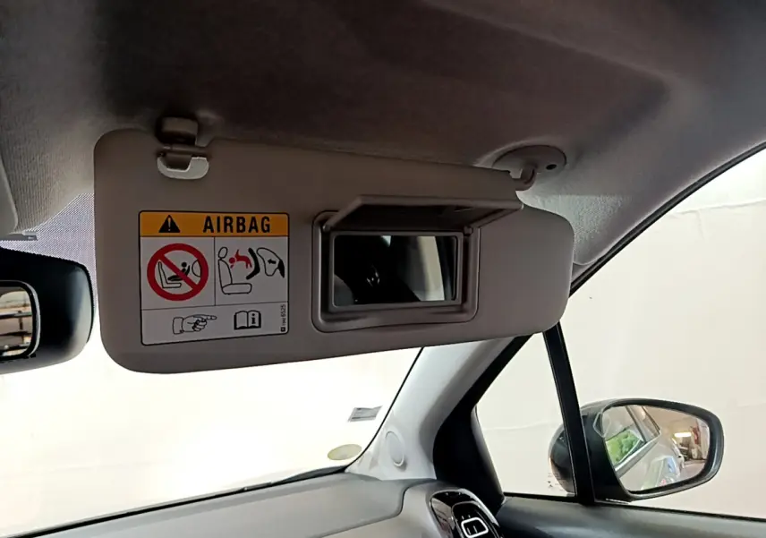 Détail du pare-soleil côté conducteur avec miroir et avertissement airbag dans l'habitacle blanc du Citroën C3 Aircross.