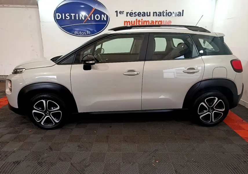 Profil droit d'un Citroën C3 Aircross blanc de 2019 avec barres de toit noires et jantes originales bicolores.
