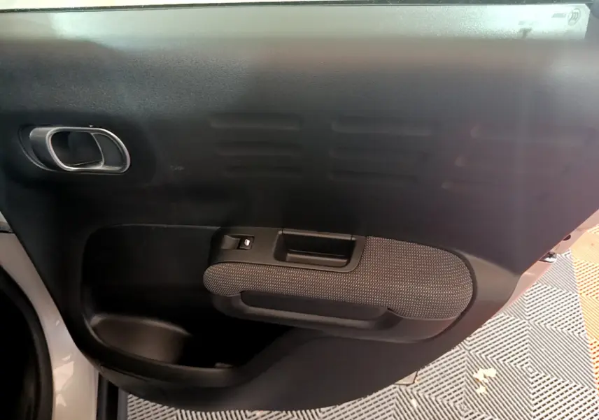 Gros plan sur la porte intérieure côté gauche d'une Citroën C3 Aircross blanc, avec poignée et tissu texturé gris.