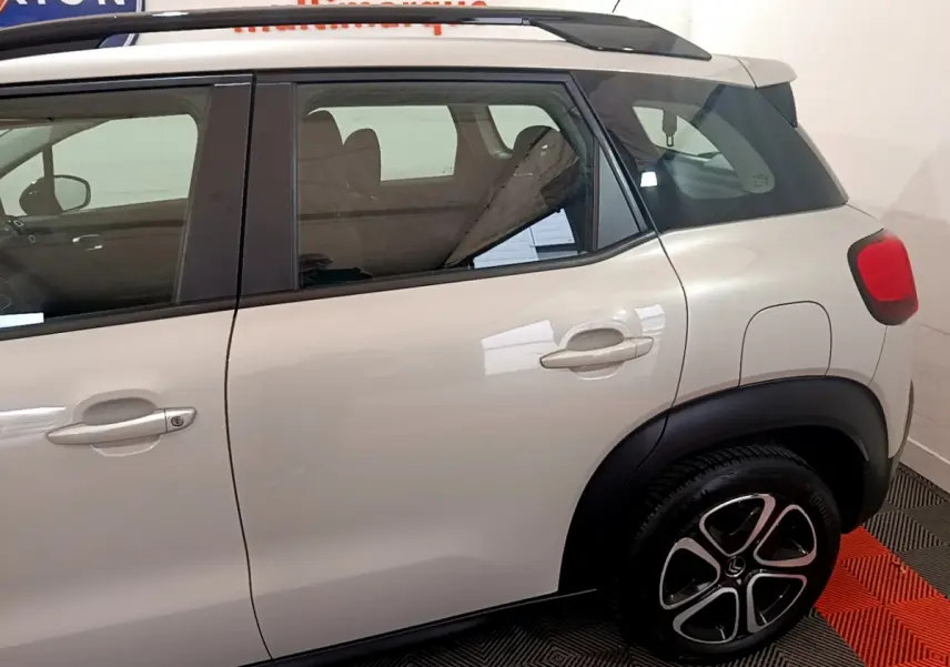 Vue latérale droite du Citroën C3 Aircross blanc, mettant en valeur les poignées de porte et les jantes noires au design distinctif.