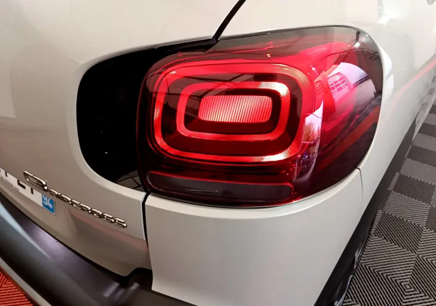 Gros plan sur le feu arrière droit rouge d'un Citroën C3 Aircross blanc, avec logo et partie arrière visibles.