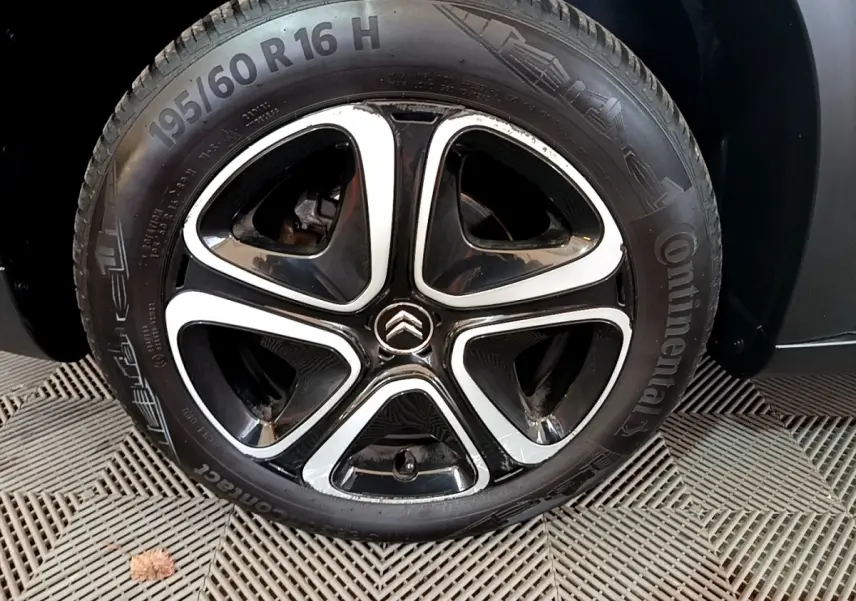 Gros plan sur la roue arrière droite d'une Citroën C3 Aircross blanche, pneu Continental visible sur sol texturé.