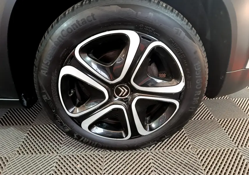 Gros plan sur la roue avant droite du Citroën C3 Aircross blanc, mettant en valeur la jante noire et argentée au design moderne.