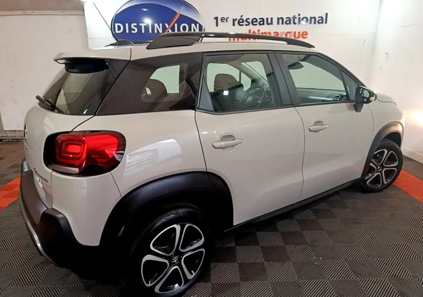 Vue 3/4 arrière droite d'un Citroën C3 Aircross blanc avec toit noir et jantes alliage distinctives.