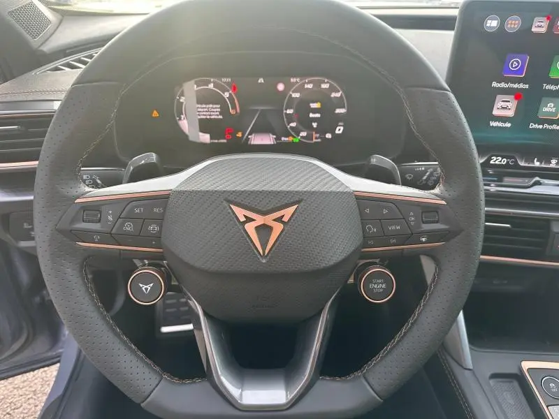 Vue rapprochée du volant perforé noir avec logo CUPRA cuivré et tableau de bord numérique du Formentor gris 2025.