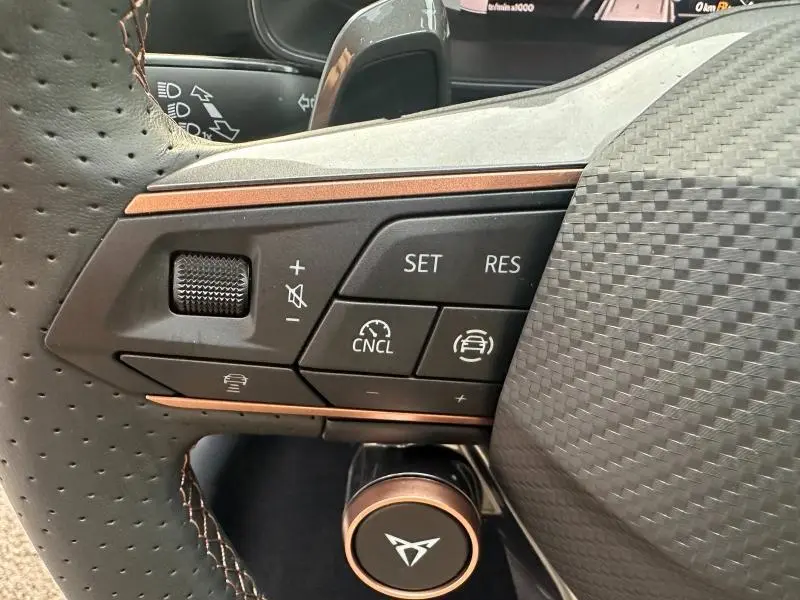 Gros plan sur les commandes à gauche du volant perforé gris du CUPRA Formentor 2.0 TDI 150ch 2025 avec finitions cuivre.