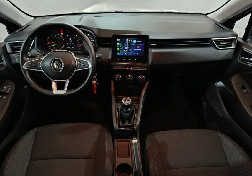 Vue intérieure avant de la Renault Clio gris clair 2023, tableau de bord avec écran tactile et volant multifonctions cuir.