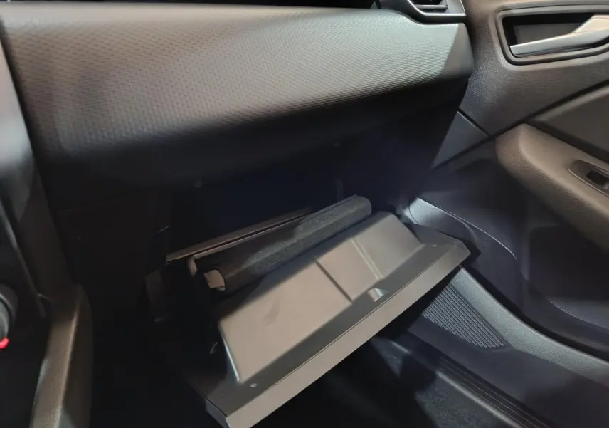 Vue intérieure côté passager de la Renault Clio gris clair 2023 avec boîte à gants ouverte et tableau de bord texturé.