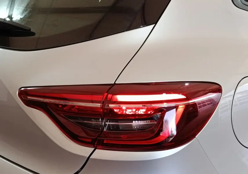 Gros plan sur le feu arrière droit rouge d'une Renault Clio 2023 gris clair, avec la trappe à carburant visible.