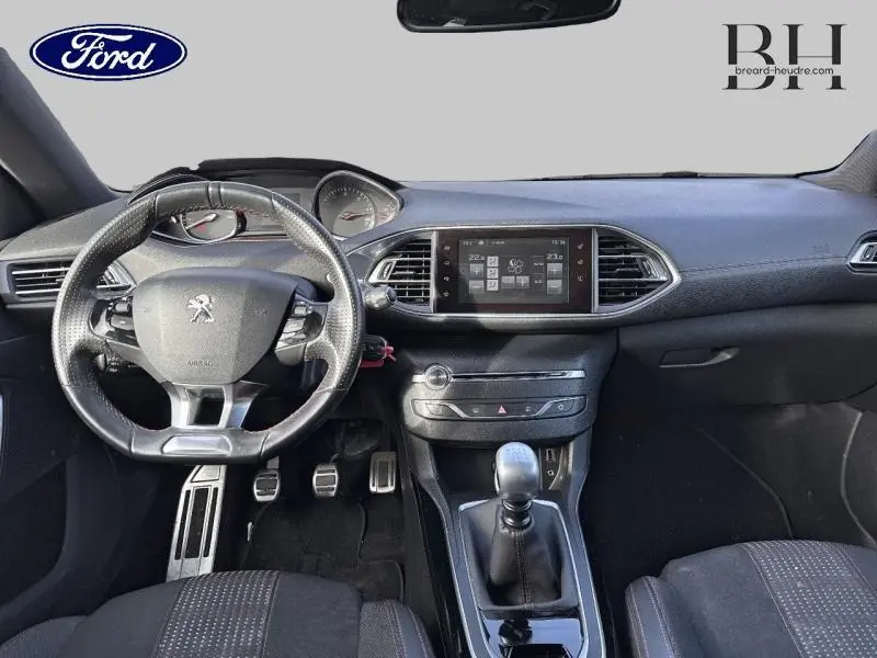 Vue intérieure avant du tableau de bord et volant cuir noir du Peugeot 308 SW gris Artense avec boîte manuelle et écran tactile multifonction.