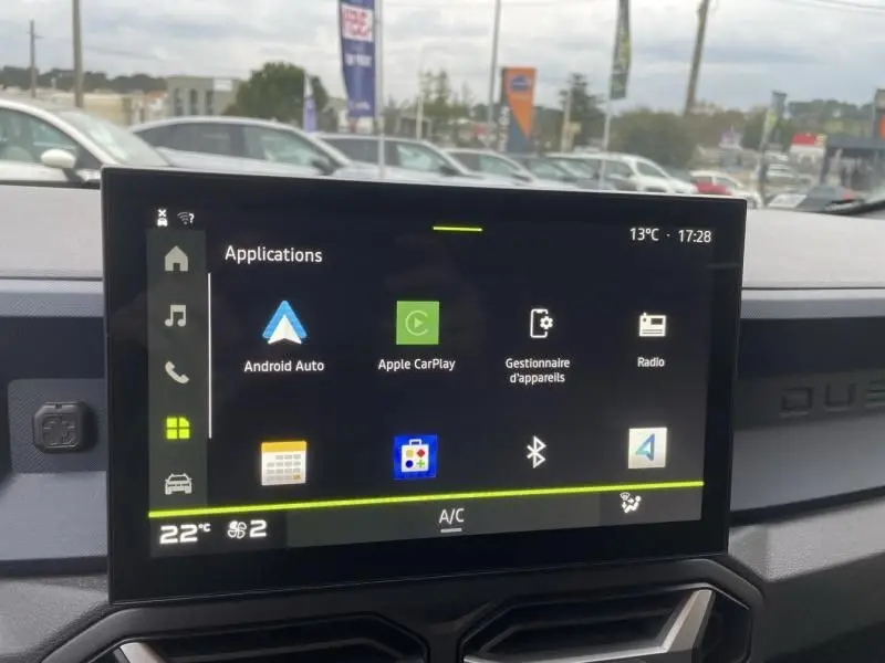 Écran tactile central du tableau de bord du Dacia Duster 2025 affichant les applications connectées, intérieur noir.