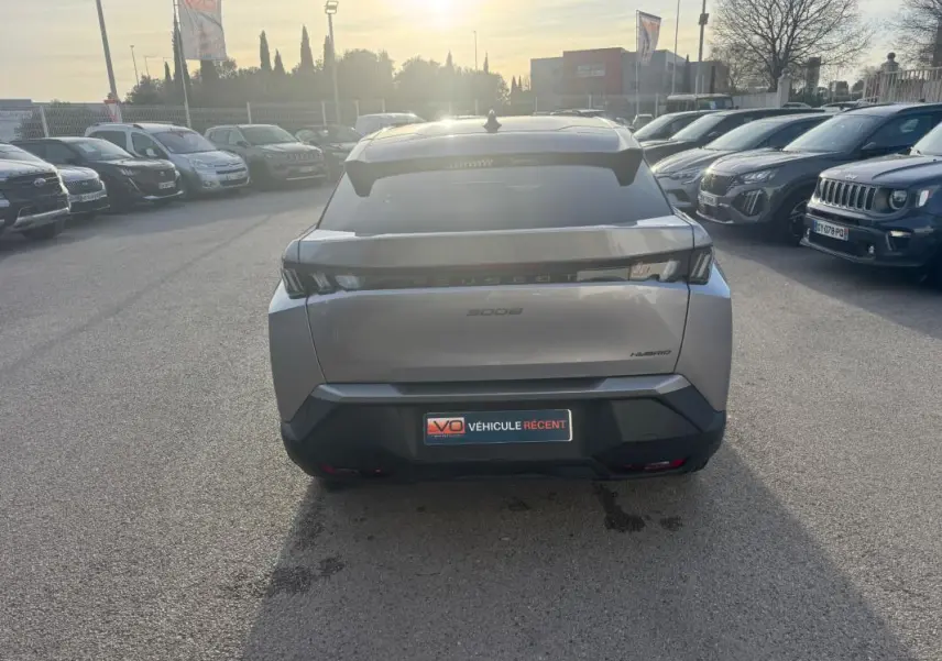 Vue arrière d’un Peugeot 3008 Hybrid gris 2025 avec feux arrière noirs et jantes alliage visibles en concession.