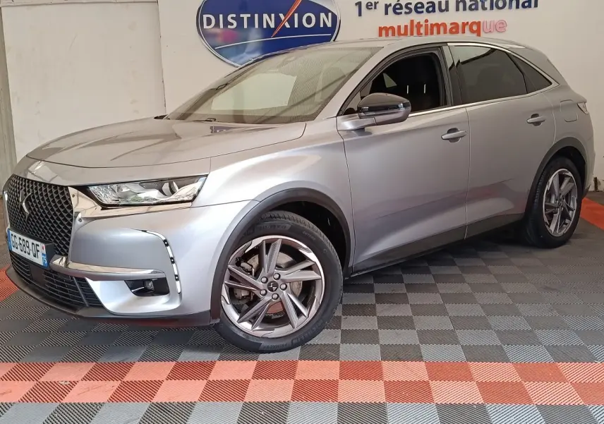 DS7 Crossback gris clair en 3/4 avant droit, avec calandre distinctive et jantes alliage modernes.
