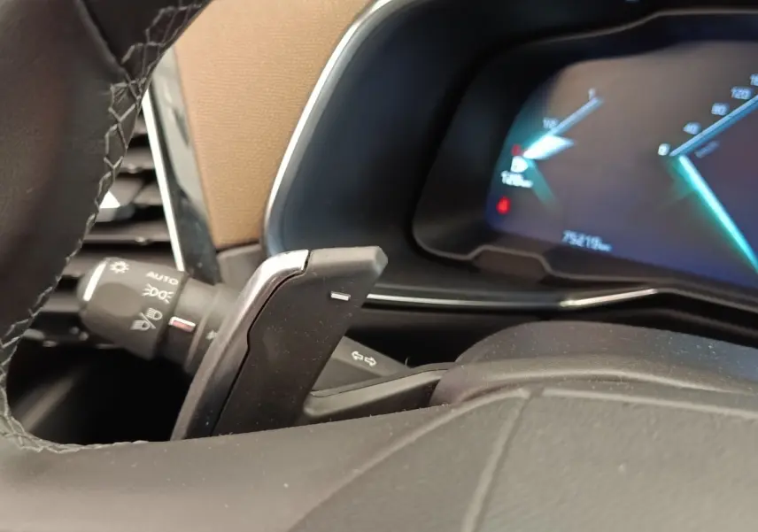 Gros plan sur le volant cuir et palettes de commande du DS7 Crossback E-TENSE 225, tableau de bord numérique en arrière-plan.