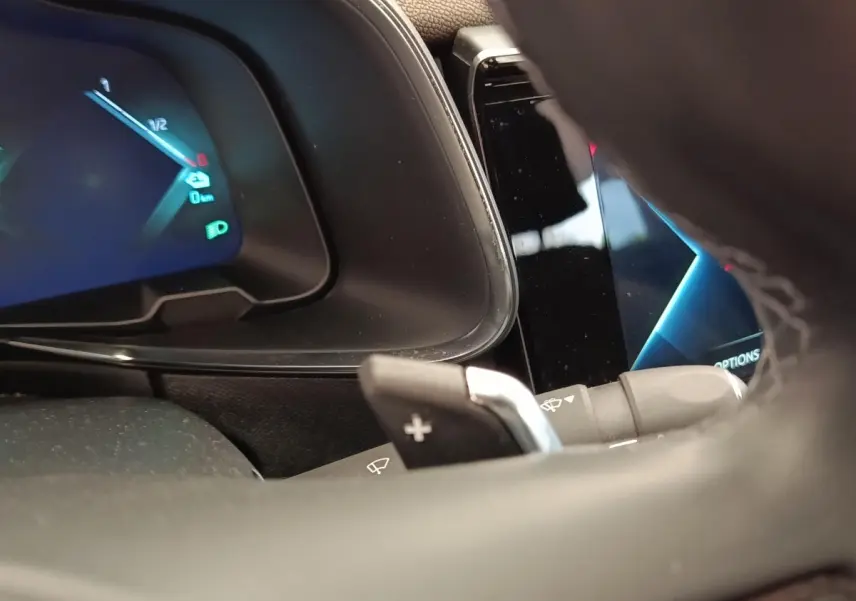 Gros plan sur le tableau de bord et le volant cuir multifonctions du DS7 Crossback E-TENSE 225 gris clair, affichage digital visible.