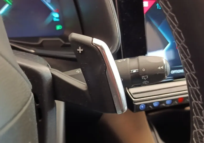 Gros plan sur la palette de changement de vitesse au volant cuir du DS7 Crossback E-TENSE 225, avec écran tactile en arrière-plan.