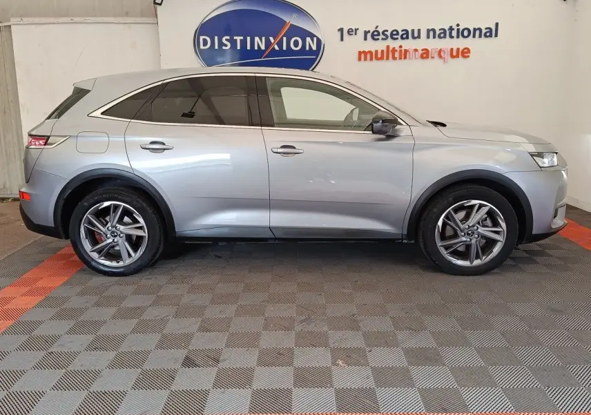 Vue de profil côté gauche d’un DS7 Crossback E-TENSE 225 Business gris clair, avec jantes alliage et vitres teintées.