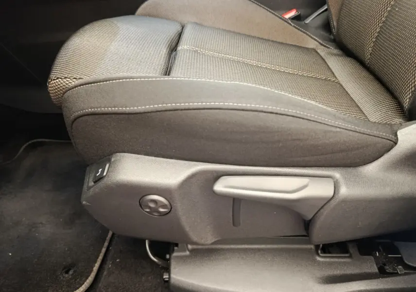 Gros plan sur le siège avant droit en tissu noir du DS7 Crossback E-TENSE 225 BUSINESS, montrant les commandes de réglage manuel.