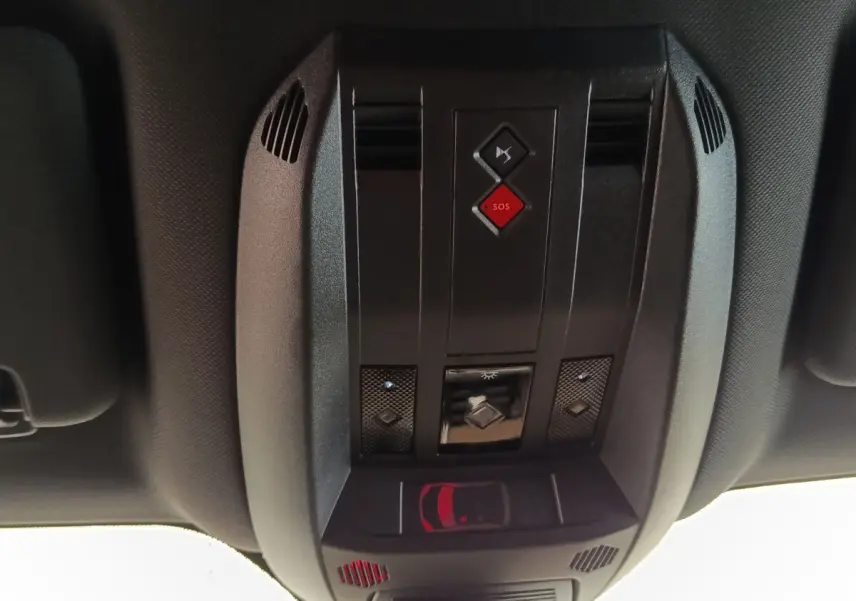 Vue en gros plan du plafonnier noir avec bouton SOS rouge et commandes d’éclairage du DS7 Crossback gris clair.