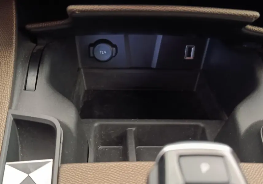 Gros plan sur la console centrale du DS7 Crossback E-TENSE 225 Business avec prise 12V et rangement noir.