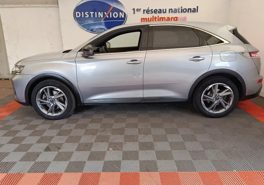 Vue de profil côté gauche d’un DS7 Crossback E-TENSE 225 Business gris clair, avec jantes alliage et vitres teintées.