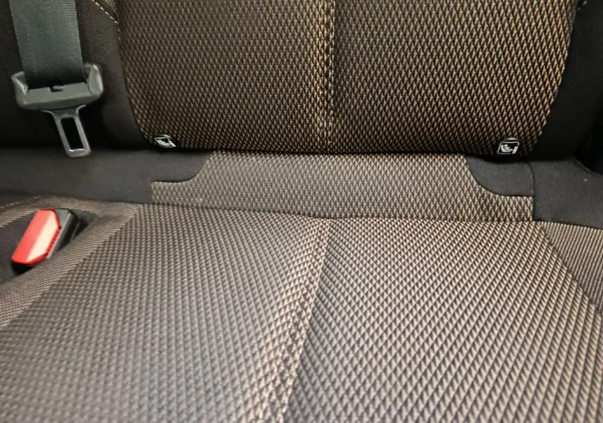 Gros plan sur la banquette arrière en tissu gris foncé avec ceinture de sécurité et fixation Isofix visible.