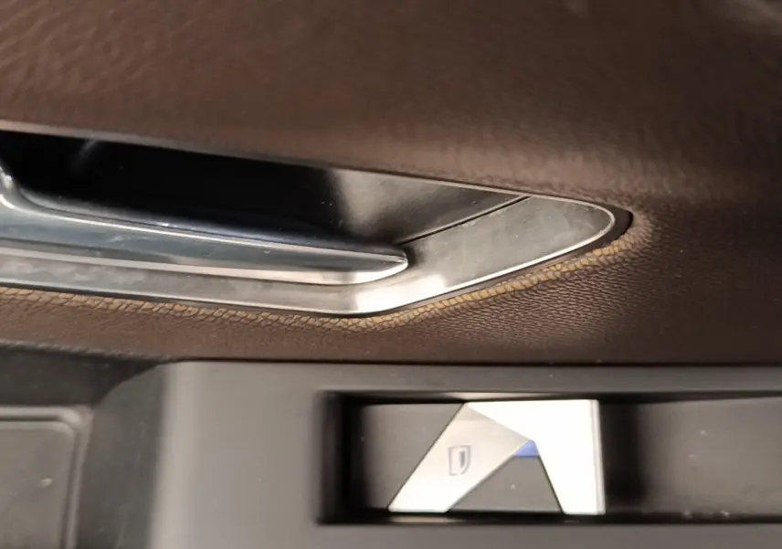 Bouton de commande de lève-vitre en métal brossé sur porte intérieure en cuir marron du DS7 Crossback gris clair.