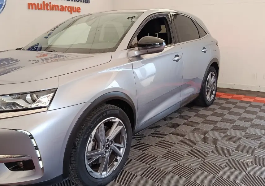 Vue 3/4 avant droite d'un DS7 Crossback E-TENSE 225 Business gris clair avec jantes alliage et feux LED allumés.