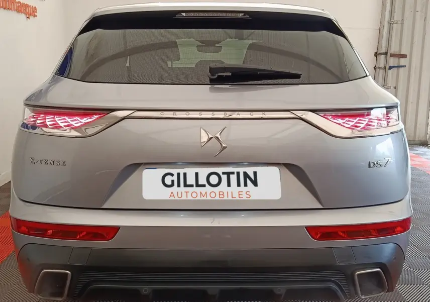Vue arrière d'un DS7 Crossback gris clair avec feux LED allumés et logo DS centré sur le hayon.