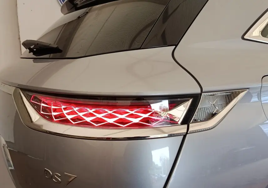 Feu arrière droit allumé sur DS7 Crossback gris clair, vue rapprochée du coin arrière droit avec lunette arrière.